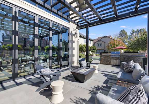 A modern outdoor patio with a glass wall and a stone fireplace.