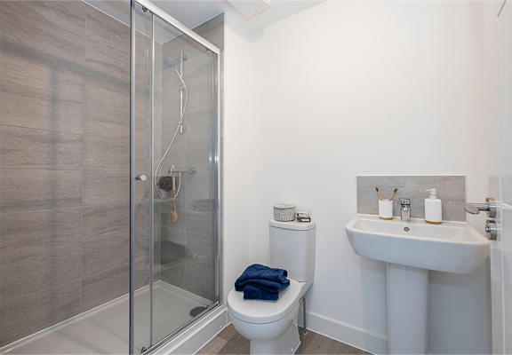 A bathroom with a toilet, sink, and shower.