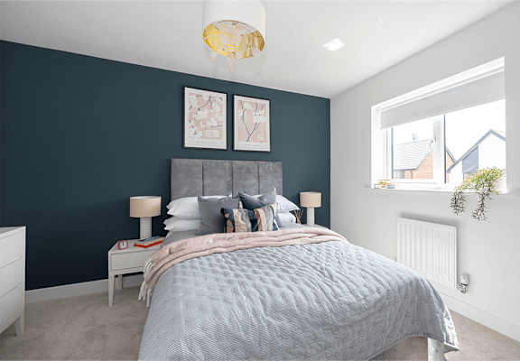 A bedroom with a bed, nightstand, and a window.
