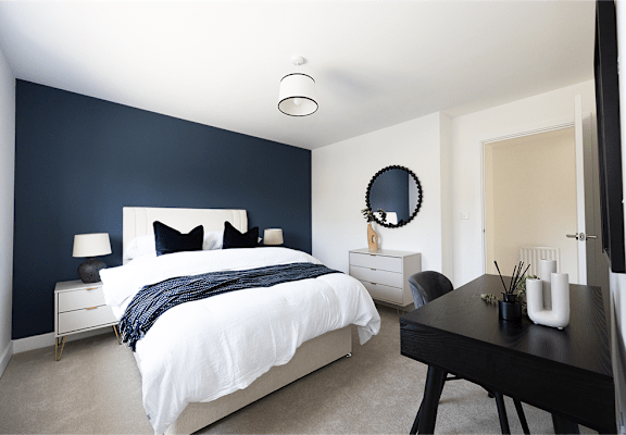 A bedroom with a white bed and a black table.