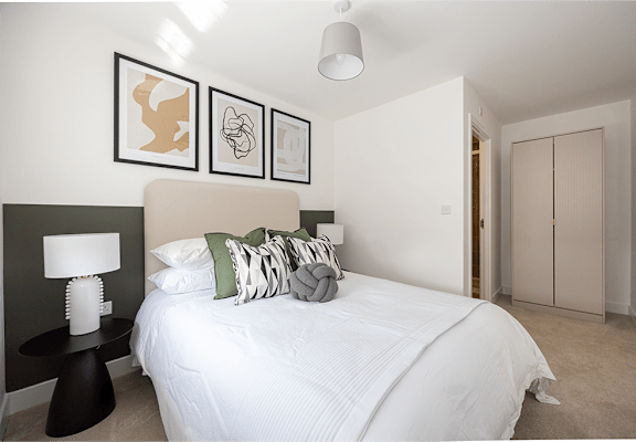 A bedroom with a white bed and green pillows.
