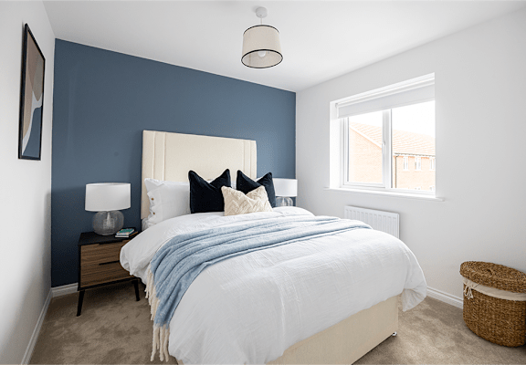 A bedroom with a white bed and a blue blanket.