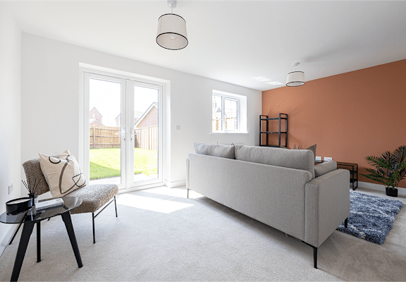 A living room with a grey couch, a chair, a small table, and a window.