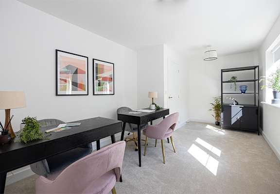 A room with a black table and pink chairs.