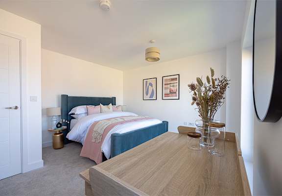 A bedroom with a bed, nightstand, and a wooden table.