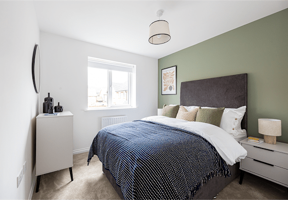 A bedroom with a bed, nightstand, and lamp.