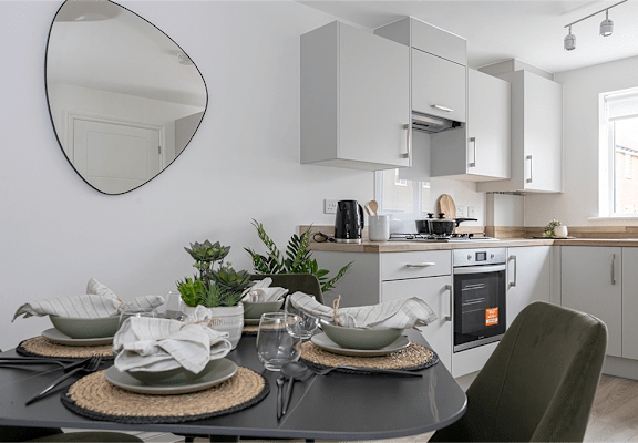 A modern kitchen with a dining table set for two.