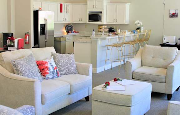 A white couch with a red pillow and a white ottoman with a red rose on it at Clarkston Station Apartments, Clarkston, GA