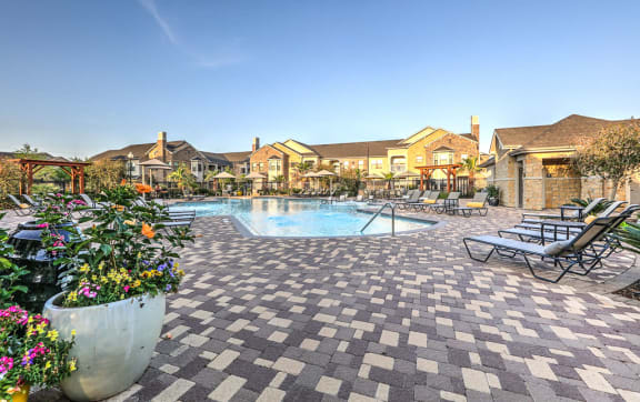 a large pool with lounge chairs and umbrellas in front of a building at The MK, Indiana