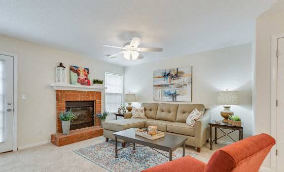 A living room with a fireplace, a couch, a chair, and a painting on the wall.