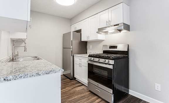 A kitchen with a black stove top oven and a marble counter top at Chelsea Place Apartments, Georgia