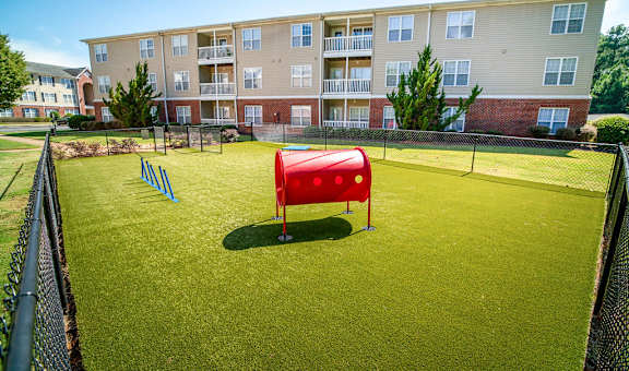 A red sandbox sits in the middle of a green field.