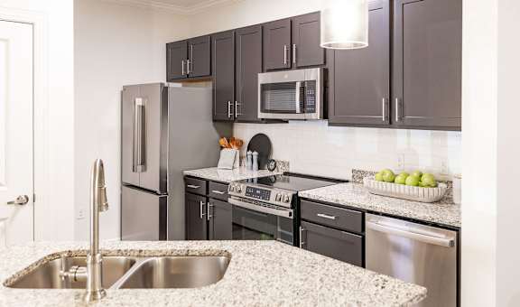 A kitchen with a sink, refrigerator, oven, and microwave.