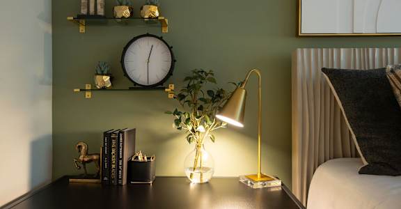 a desk with a lamp and a clock on a wall