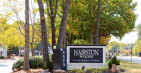a sign for harrison woods apartments in front of trees