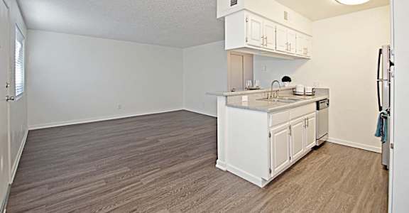 an empty kitchen and living room with white cabinets and a counter top