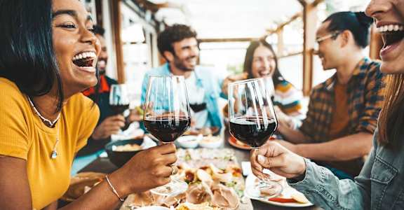 A group of people are enjoying a meal and drinks together at a table.