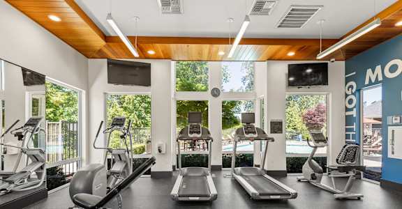 A gym with treadmills, elliptical machines, and a weight bench.