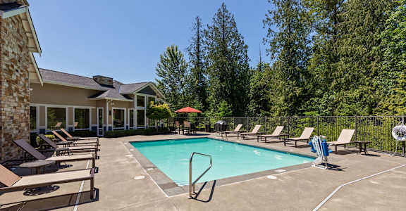 A swimming pool surrounded by lounge chairs and trees.