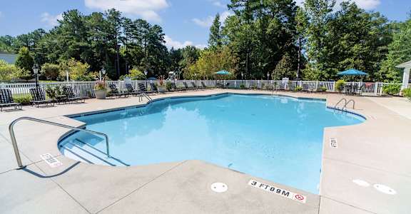 A large swimming pool surrounded by trees and a fence.
