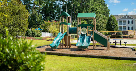 A playground with a green slide and a wooden structure.