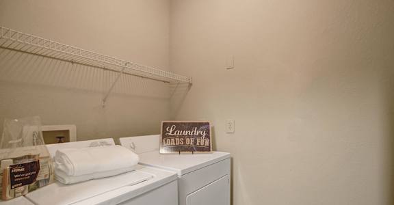 A laundry room with a washer and dryer and a sign that says "Laundry Loads of Fun".