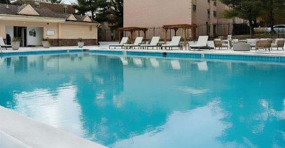 A swimming pool with lounge chairs and a building in the background.