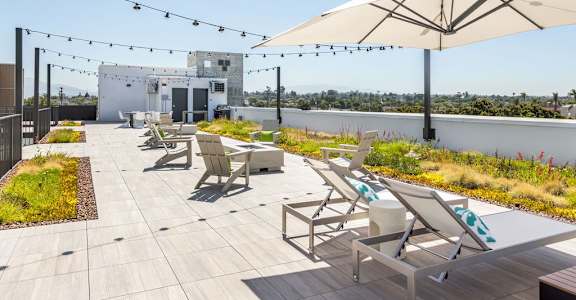 A patio with chairs and umbrellas is set on a rooftop.