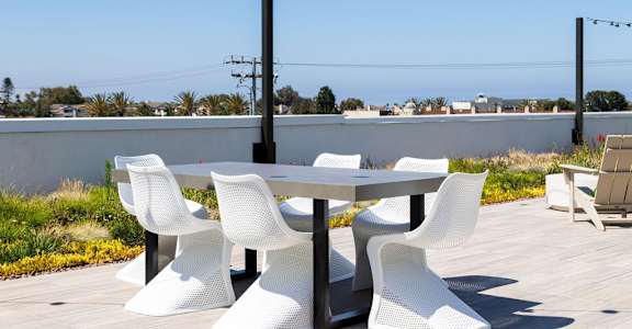 A white table and chairs are set up on a wooden deck.