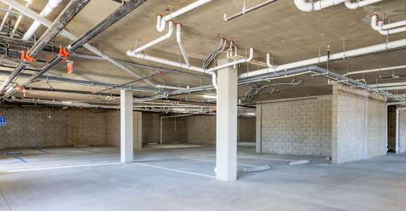A large, empty industrial space with concrete floors and exposed pipes.