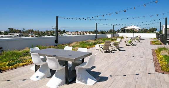 A patio with a table and chairs is decorated with string lights.