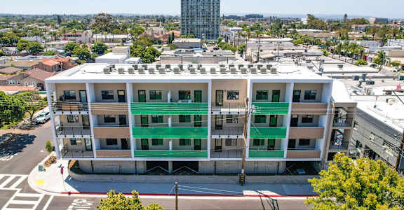 A large white building with green stripes on the windows and balconies.