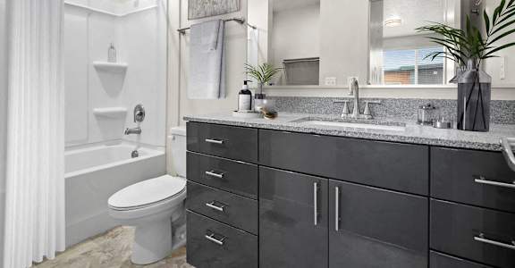 A bathroom with a white toilet, a white shower curtain, and a black cabinet.