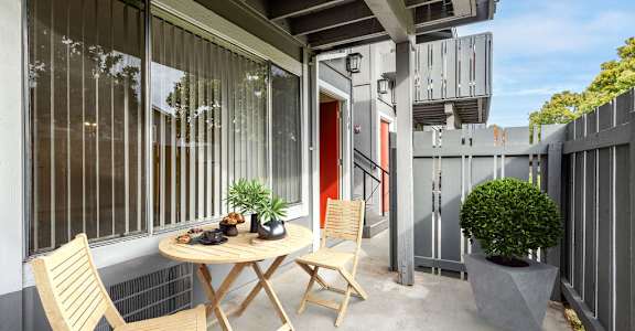 A small table with two chairs is on a patio at Cherrywood Apartments, California