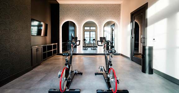 Two stationary bikes are in a room with arched windows at Evolve St. James Apartment Homes Apartments, Southport, NC, 28461