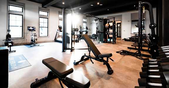A gym with a variety of equipment including weights and benches at Evolve St. James Apartment Homes Apartments, Southport, NC, 28461