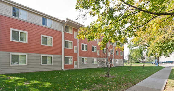 Apartment building with a sidewalk and trees in front.