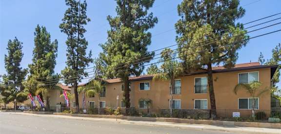A row of houses with trees in front of them.