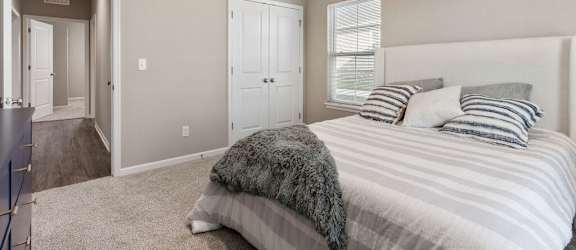 A bedroom with a bed, pillows, and a window.