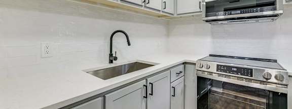 A modern kitchen with a stainless steel oven and white cabinets.