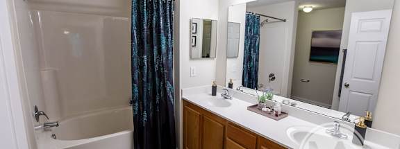 A bathroom with a white sink and a shower with a black and blue curtain.