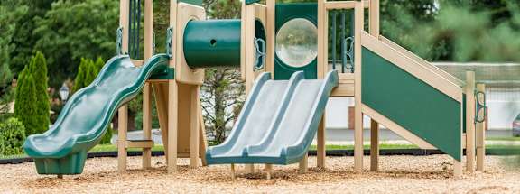 A playground with a green slide and a wooden structure.