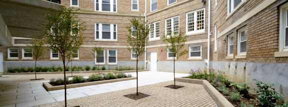 a courtyard with trees and a brick building