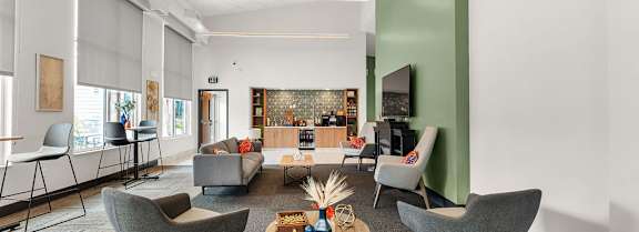 A room with a long table and chairs with a television on the wall.