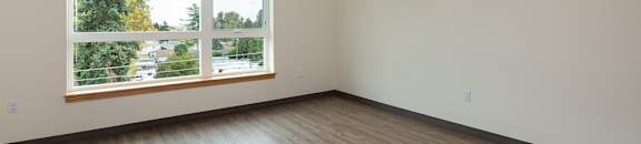 A room with a large window and wooden flooring.