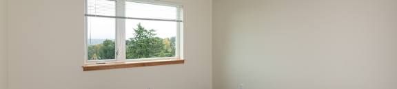 Empty room with a window and wooden floor.