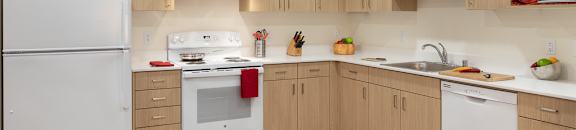 A kitchen with white appliances and wooden cabinets.
