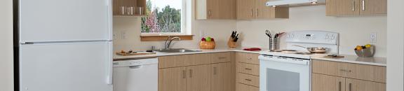 A kitchen with white appliances and wooden cabinets.