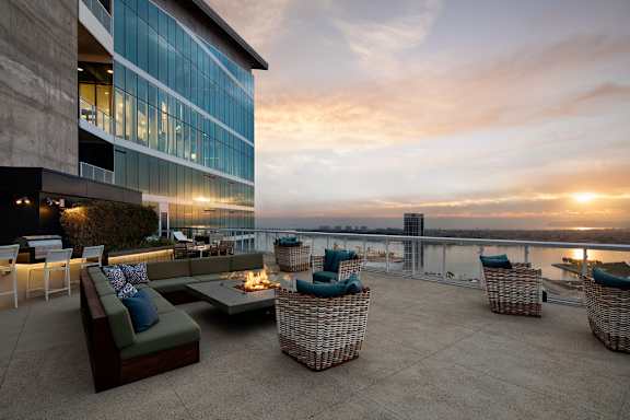 A rooftop patio with a couch, chairs, and a table with a lit candle.
