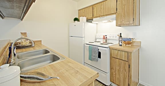 a kitchen with a white refrigerator freezer next to a white stove top oven